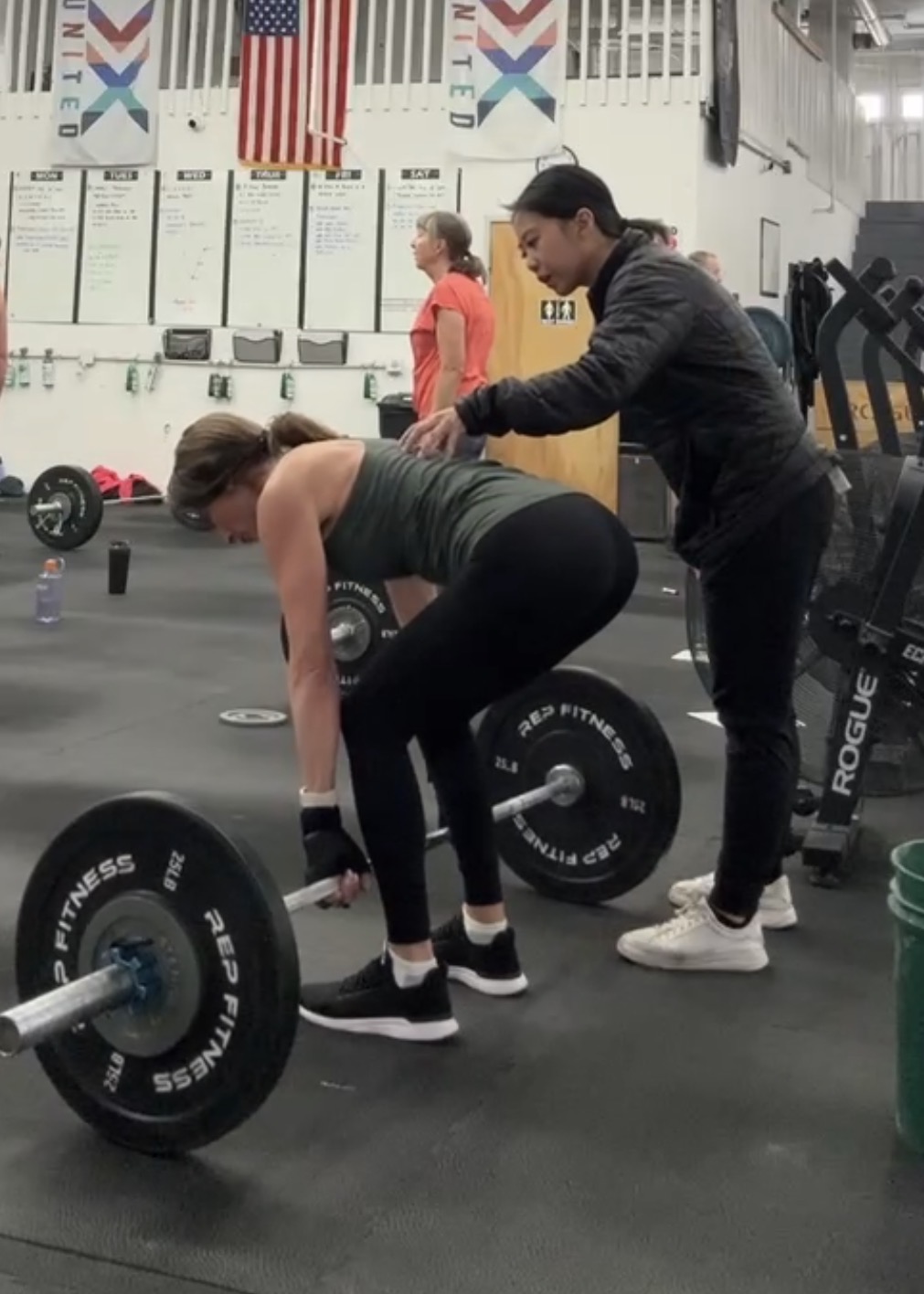 Dr. Erica Tran coaching a woman through a barbell deadlift
